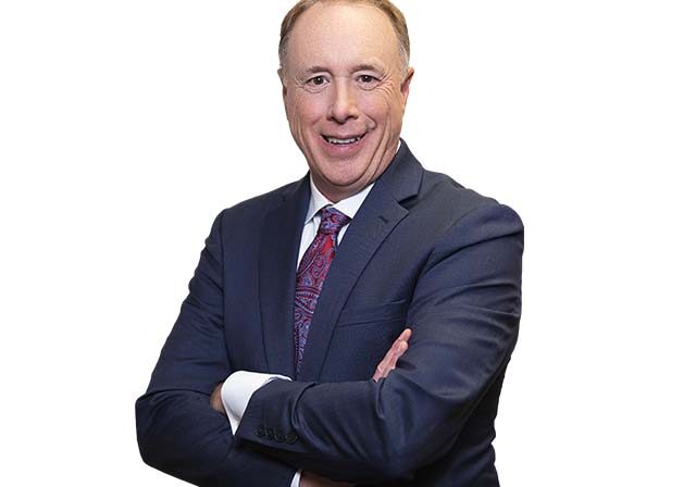 Mark Cunningham smiling wearing a suite Headshot of Mark Cunningham smiling