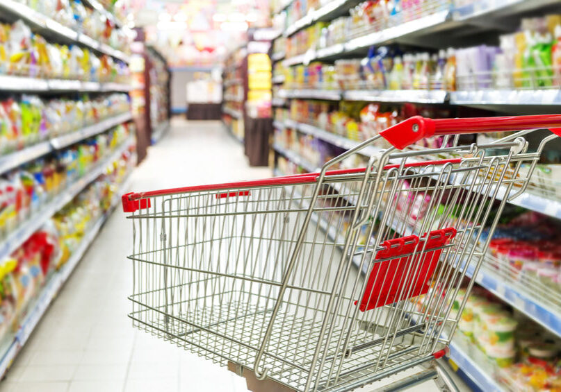 Supermarket interior, empty red shopping cart. MCIS Lawyers